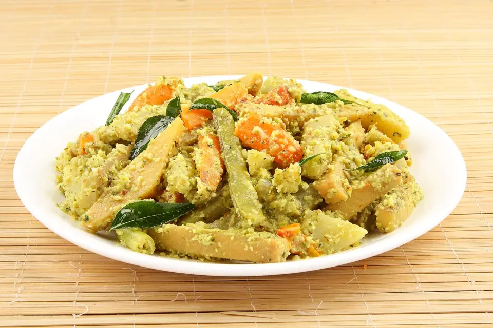 A plate of aviyal with carrot batons and curry leaves in coconut paste